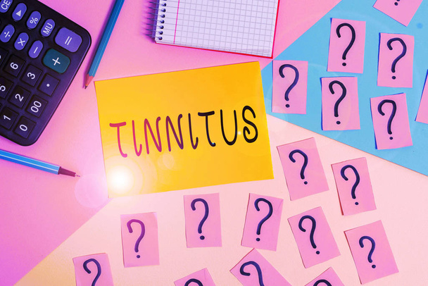 Conceptual hand writing showing Tinnitus. Business photo text A ringing or music and similar sensation of sound in ears Mathematics stuff and writing equipment on pastel background. - Photo, Image