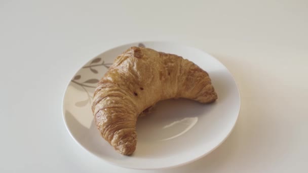 Franse croissants op een bord, sluiten. Voorraadbeelden. Heerlijke vers gebakken krokante croissant liggend op de plaat op houten tafel achtergrond. - Video