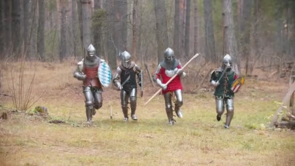 Cuatro hombres caballeros corriendo en fila en el bosque con armadura completa
 - Metraje, vídeo