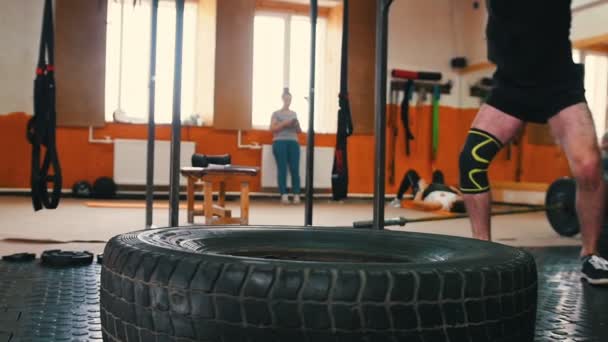 Спортивная тренировка - мужчина бьет по большой шине металлическим молотком в тренажерном зале
 - Кадры, видео