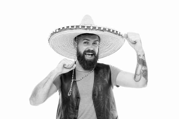 Adding hat to his spanish costume. Bearded man smiling in traditional sombrero hat. Happy hipster with beard and mustache wearing casual clothes and mexican hat. Mexican man in traditional straw hat - Fotó, kép