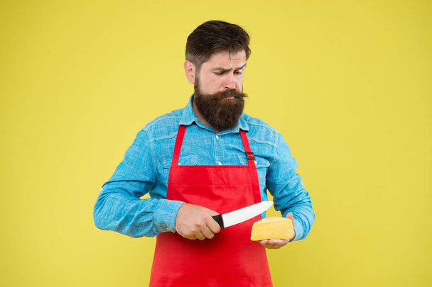 expertise cheese taste. ciet and nutrition. serious bearded man cut cheese with knife. cheesemaking concept. cheesemaker own business. hipster beard in chef apron. Dairy food shop. cheese festival - Foto, imagen