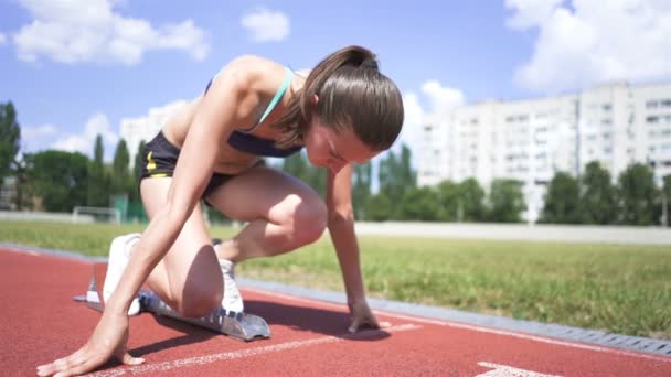 Mladá dívka sportovec začít běžet z bloku na městském stadionu. Zpomalený pohyb, stálý výstřel - Záběry, video