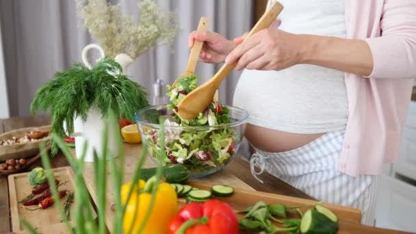 Těhotná žena dělá čerstvý zelený salát v kuchyni. Closeup. - Záběry, video