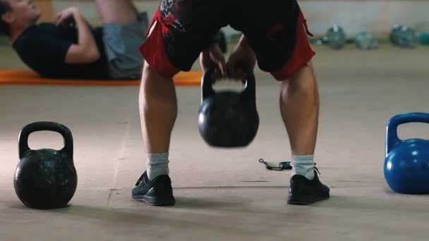 Sportliches Training - ein athletischer Mann in roten Shorts hockt mit einem Gewicht in den Händen - Filmmaterial, Video