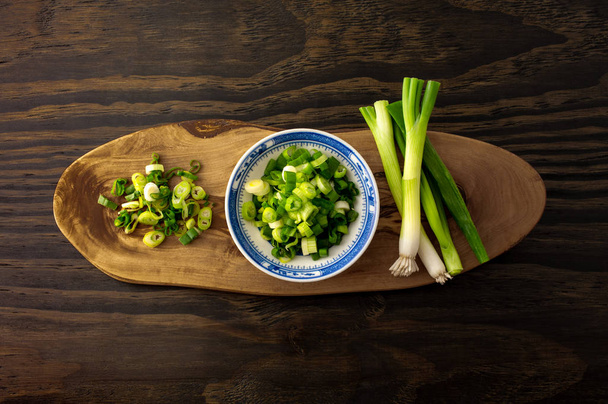 Chopped spring onion, scallion on wood board and wood background. - Foto, Imagen