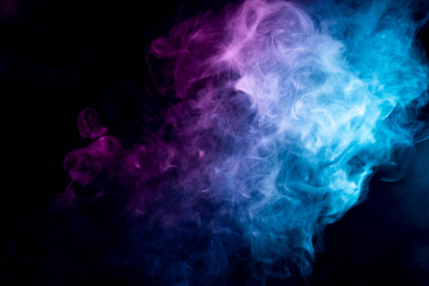 Transparent creativity. Abstract art colored  pink and blue smoke on black isolated background. Stop the movement of multicolored smoke on dark backgroun - Photo, Image