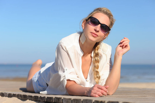 Girl in sunglasses on background of sky - Foto, afbeelding