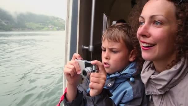Mother with son float at passengers vessel, boy makes photo - Filmati, video