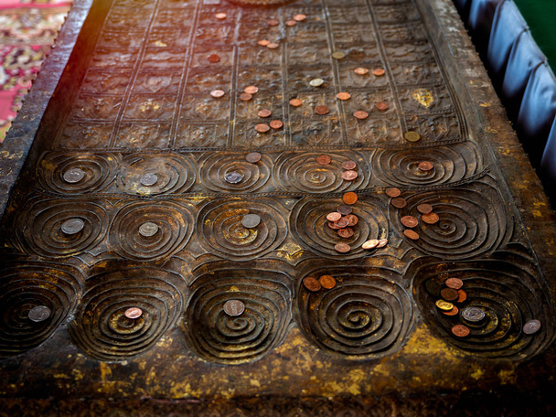 Muchas monedas colocadas en la réplica de la huella de buddha en el templo
. - Foto, Imagen