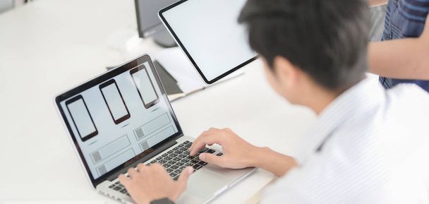 Vista de close-up do planejamento do designer gráfico UI em seu aplicativo de modelo de smartphone com computador portátil
  - Foto, Imagem