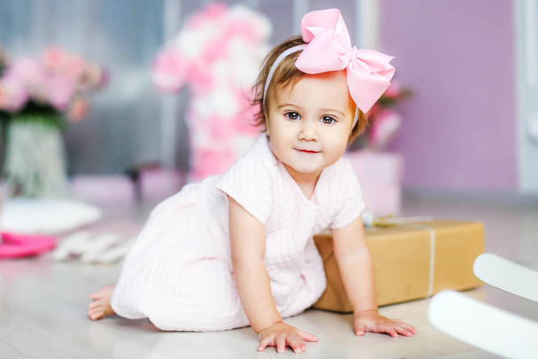 Baby with a pink dress on a background of pink adornment with a pink bow on her head - Photo, Image
