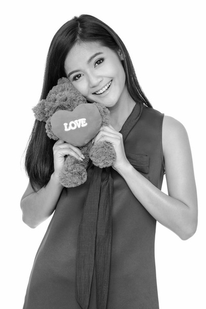 Молодий красиві азіатські жінки, що тримає плюшевий ведмідь з серцем і любов знак - Фото, зображення