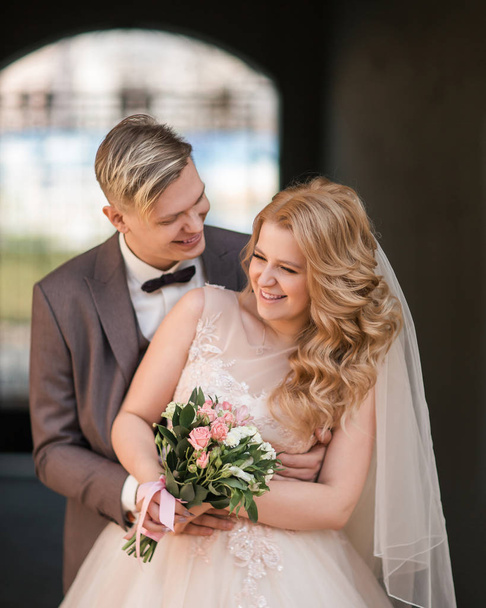 bride and groom standing under the arch of the city building. - Fotografie, Obrázek