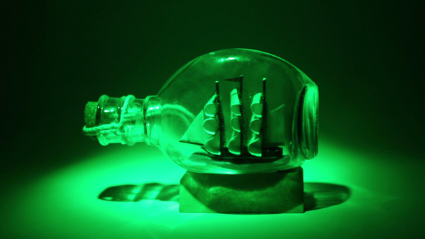 tallship w szklanej butelce oświetlone przez colorfull reflektor w ciemności - Materiał filmowy, wideo