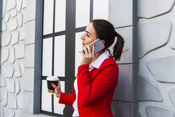 деловая женщина держит кофе и разговаривает по телефону
 - Фото, изображение