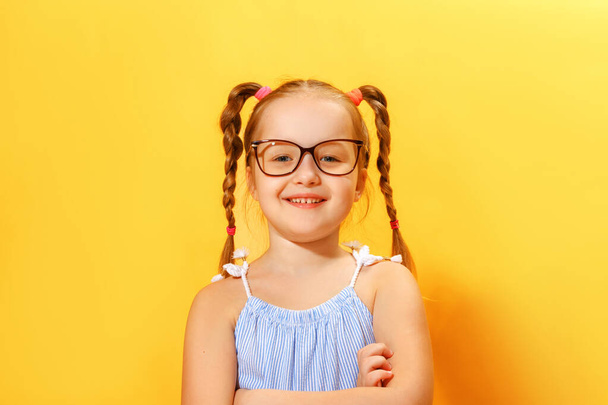 Portrait of a funny little girl of preschool child with glasses on a yellow background - Foto, immagini