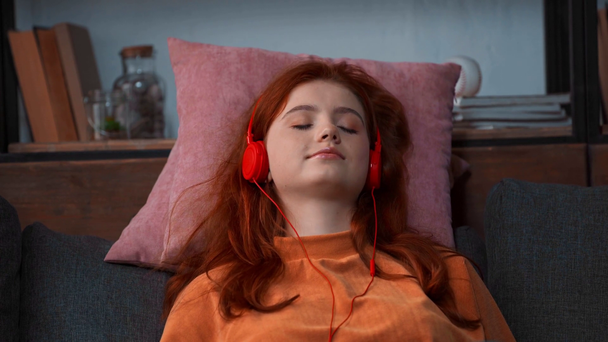 ευτυχισμένη κοκκινομάλλα έφηβη κοπέλα ακούγοντας μουσική στα ακουστικά - Πλάνα, βίντεο