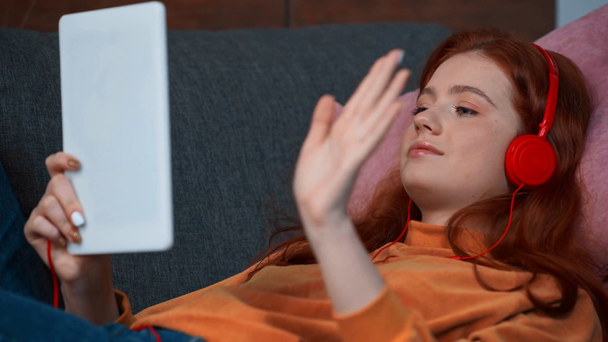 pozytywna nastolatka w słuchawkach za pomocą tabletu cyfrowego - Materiał filmowy, wideo