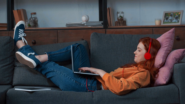 cheerful teenage girl lying and chatting on laptop - Footage, Video