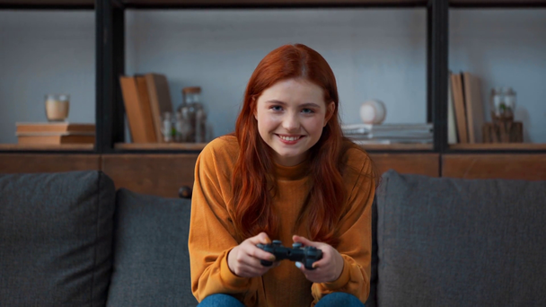 KYIV, UKRAINE - NOVEMBER 8, 2019: excited redhead teenage girl playing video game  - Кадри, відео