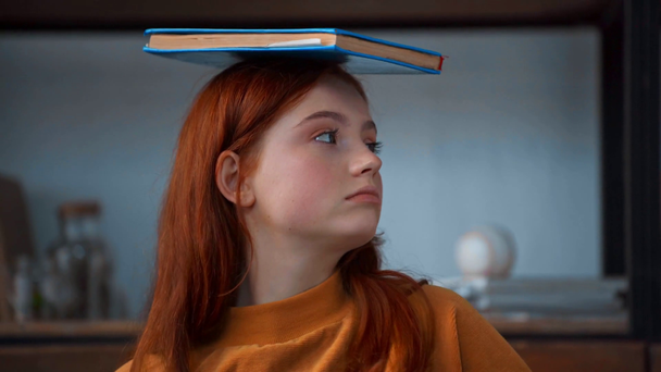 cheerful redhead teenage girl having fun with book - Filmati, video
