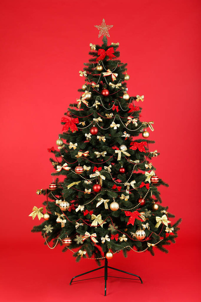 Christmas fir tree with ornaments on red background - Photo, Image