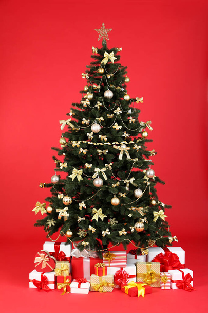Christmas fir tree with ornaments and gift boxes on red background - Fotoğraf, Görsel