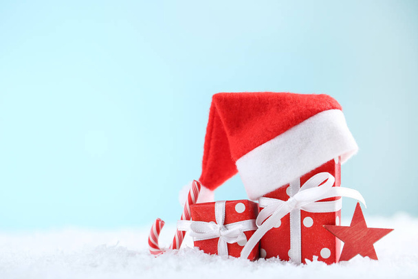 Kırmızı Noel Baba şapkası hediye kutuları ve mavi arka planda şekerler. - Fotoğraf, Görsel