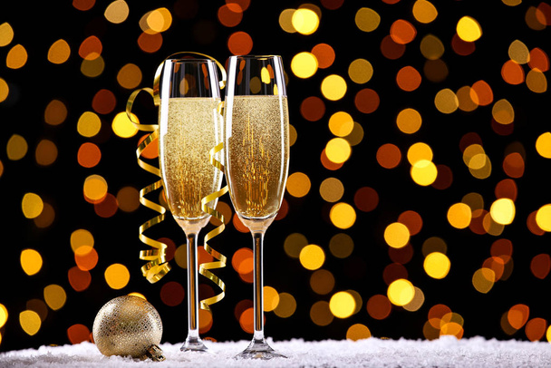 Lunettes de champagne avec boule de Noël et ruban sur fond de lumières floues
 - Photo, image