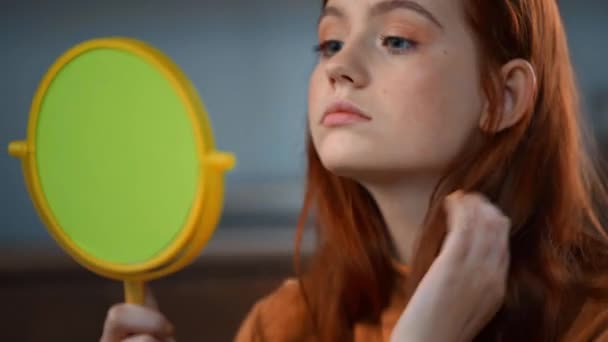 teenage girl looking at cosmetic mirror, touching face and hair - Footage, Video
