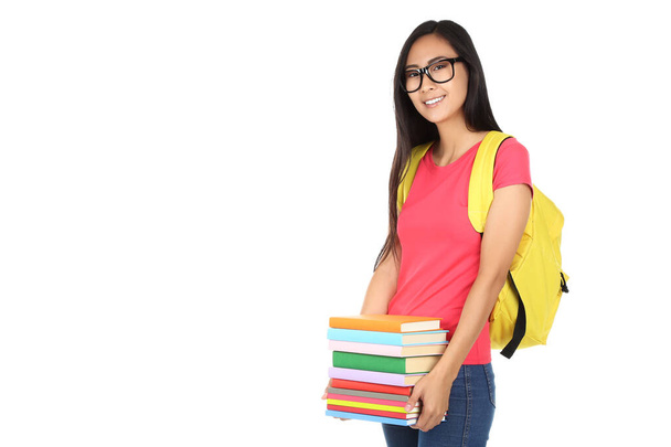 Young woman with books and backpack on white background - Valokuva, kuva