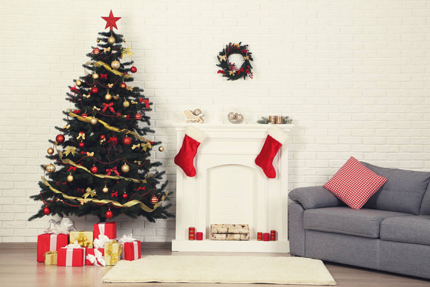 Christmas fir tree with ornaments and gift boxes near decorated fireplace at home - Fotoğraf, Görsel