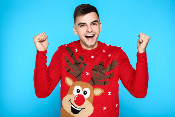 Beautiful man in red christmas sweater on blue background - Foto, imagen