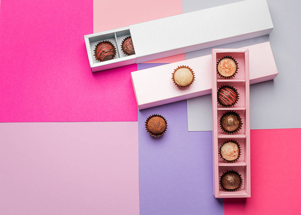 Assorted chocolates in pink blue boxes on a background of colored paper background. Flat top view. Copy space. Holiday - 写真・画像