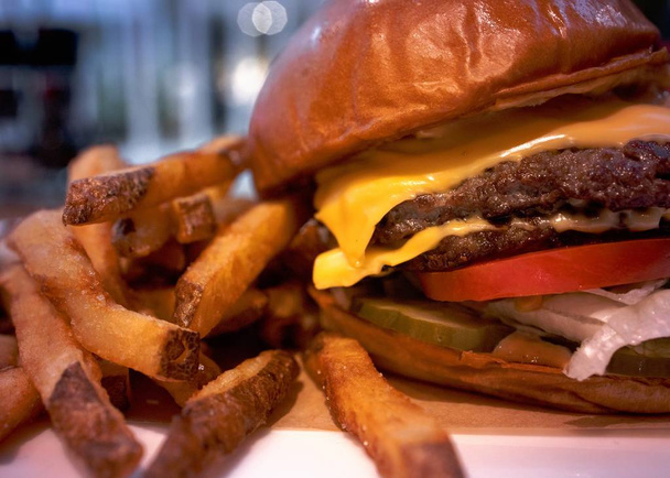 A closeup shot of tasty hamburger with french fries on a blurred background - Φωτογραφία, εικόνα