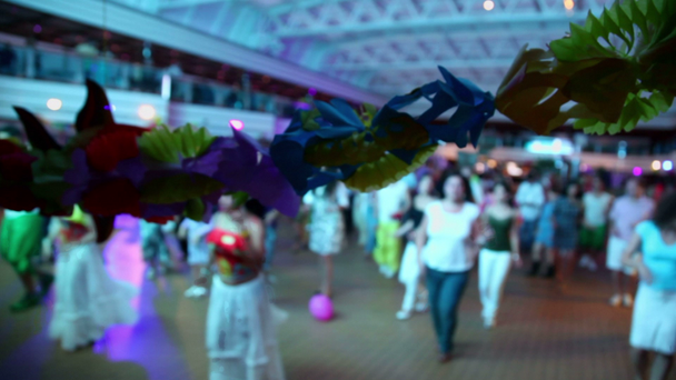 spousta lidí tanec v hale, zaměření na věnec z papírových květin - Záběry, video
