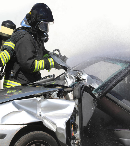 strażak używa nożyc do otwarcia uszkodzonego samochodu - Zdjęcie, obraz
