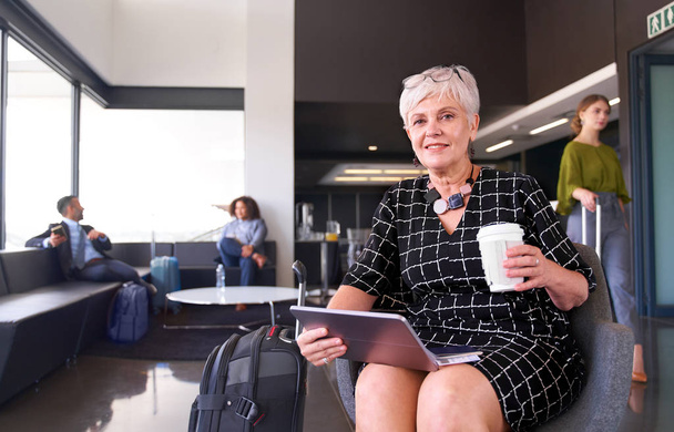 Επαγγελματική γυναίκα που κάθεται στο αεροδρόμιο φορώντας μοντέρνο φόρεμα smili - Φωτογραφία, εικόνα