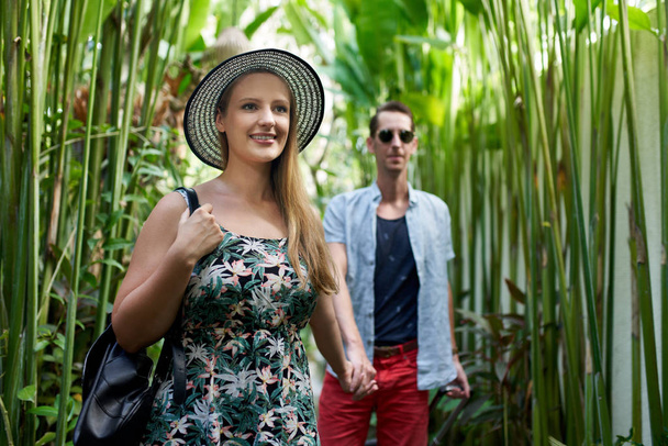 Молода щаслива пара хіпстерів тримає руки в тропічній рослині
 - Фото, зображення