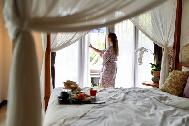 Young serene woman wearing bathrobe indoors opening luxurious ho - Foto, imagen