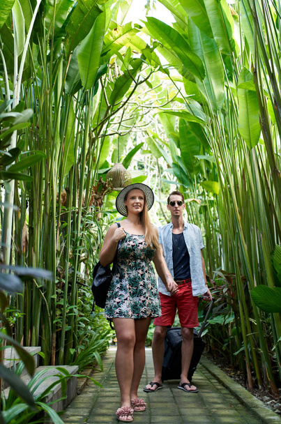 Young happy hipster couple holding hands in tropical plant passa - Photo, Image