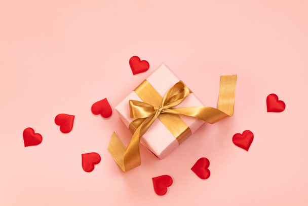 Gyönyörű ajándék csomagolás doboz piros íj és a szeretet szív alakú rózsaszín háttér. - Fotó, kép