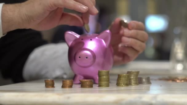 Oszczędzam pieniądze. mężczyzna ręce wprowadzenie monety w świnka bank - Materiał filmowy, wideo