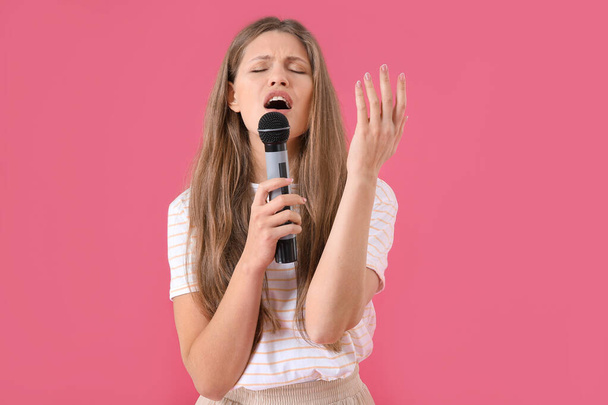 Beautiful young female singer with microphone on color background - Фото, зображення