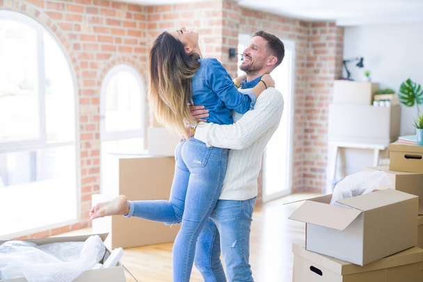 Young beautiful couple holding stack of cardboard boxes at new home - Photo, Image