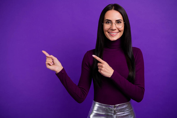 Photo of cheerful positive cute pretty nice business woman pointing into empty space smiling toothily isolated purple vibrant color background - Фото, изображение