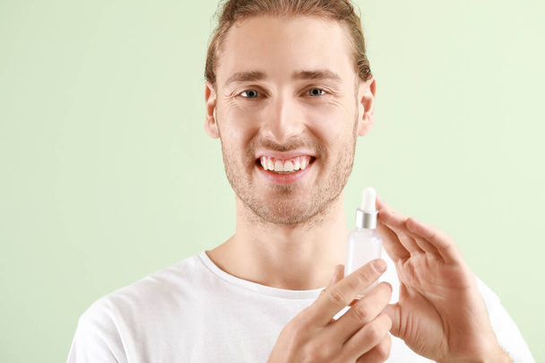 Handsome young man with cosmetic product on light background - Foto, Imagem