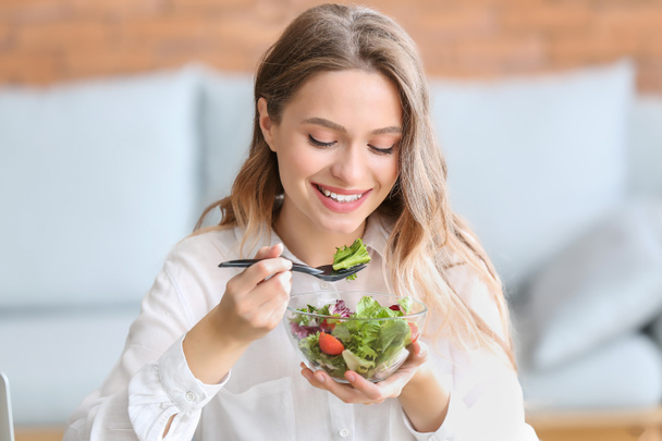 Woman eating healthy vegetable salad in office - Фото, изображение