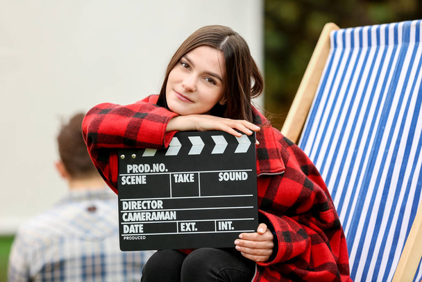 Счастливая молодая женщина с фильмом хлопает в открытом кино
 - Фото, изображение
